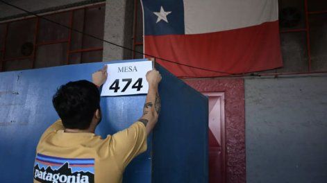 Un empleado municipal pone el cartel indicativo de una mesa electoral en el Estadio Nacional de Santiago el 13 de diciembre de 2025, víspera de la segunda vuelta de las elecciones presidenciales de Chile.