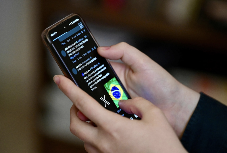 Un usuario brasileño de la red social X, antes Twitter, consulta publicaciones en un teléfono celular en Brasilia