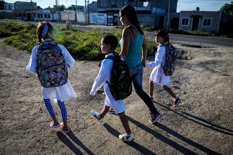 Una madre con niños camino a la escuela, en barrio Santa María (Casavalle)