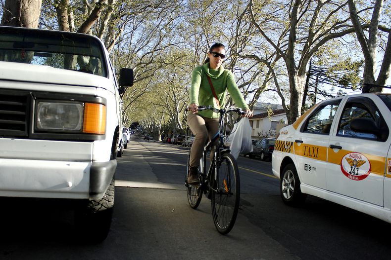 Mujer recorre en bicicleta una calle de Montevideo.