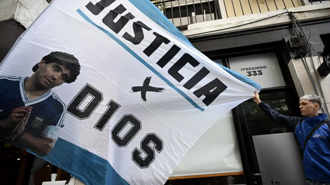 Un aficionado sostiene una bandera con la imagen del fallecido Diego Maradona antes del juicio por la muerte de la leyenda del fútbol argentino Diego Maradona en San Isidro, provincia de Buenos Aires, Argentina, el 11 de marzo de 2025