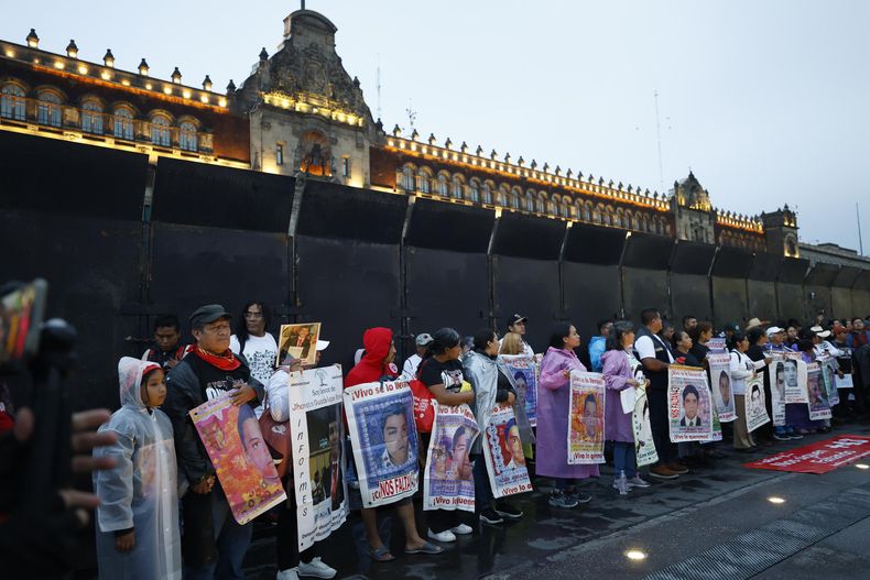 Personas sostienen carteles en una protesta por el aniversario de la desaparición de 43 estudiantes de Ayotzinapa, este viernes en Ciudad de México (México).&nbsp;