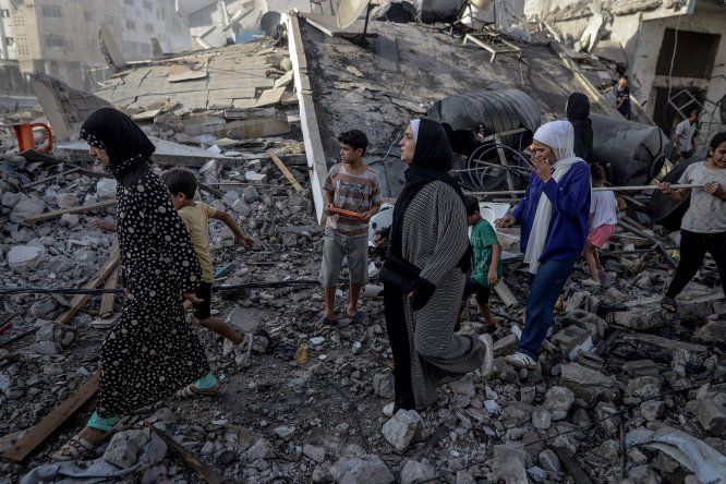 Personas, caminando sobre escombros, abandonan la zona tras el ataque israelí en la calle Omar al-Mukhtar de la ciudad de Gaza, el 3 de octubre de 2025.