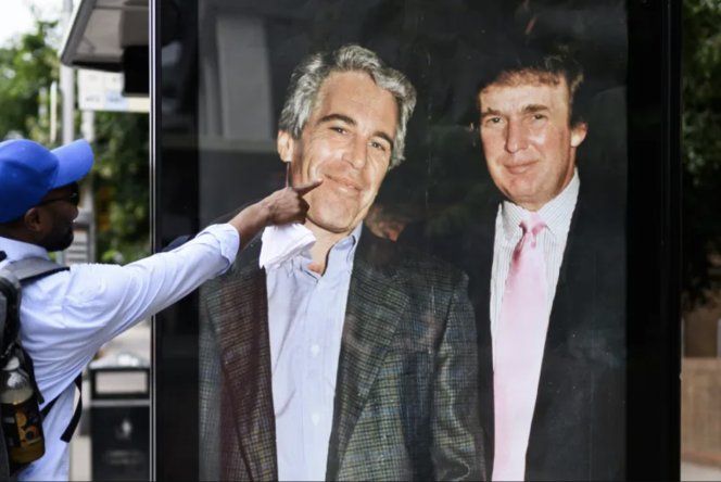 Un hombre señala una fotografía de Donald Trump y Jeffrey Epstein colocada extraoficialmente en una parada de ómnibus el 17 de julio en Londres de 2025.