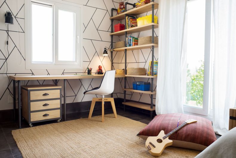 Estanterías en metal y un gran escritorio en madera forman parte del diseño del dormitorio
