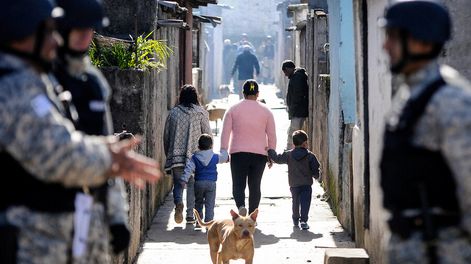 Una mujer camina con sus hijos en el complejo de la Unidad Misiones, conocido como Los Palomares de Casavalle, Montevideo. Foto: Javier Calvelo/ adhocFOTOS