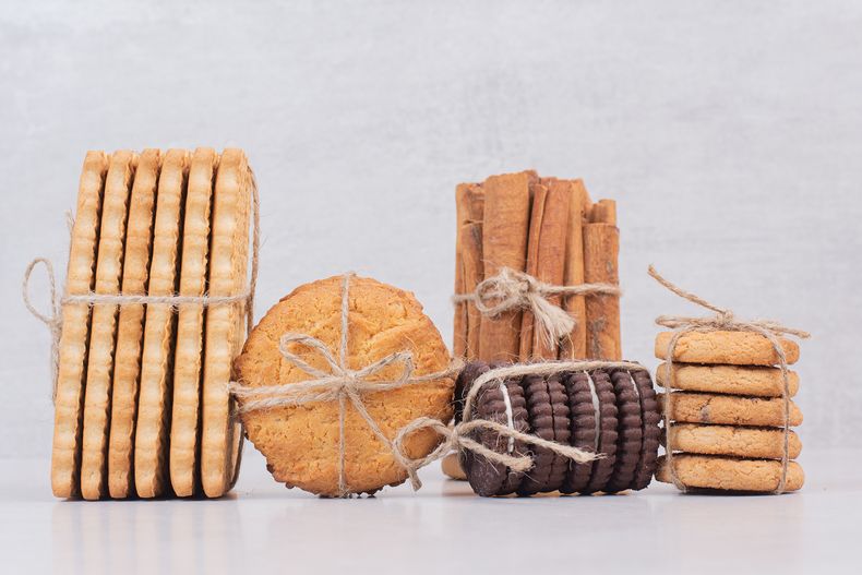 galletas-en-cuerda-con-canela-en-rama-sobre-mesa-blanca.jpg