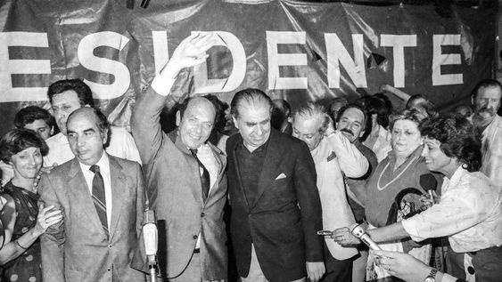 Alberto Zumarán y Julio María Sanguinetti, tras conocerse los resultados de las elecciones nacionales. A la izquierda, Aquiles Lanza. Atrás, a la derecha, Enrique Tarigo. Sede del Partido Colorado. 25 de noviembre de 1984 Alberto Zumarán y Julio María Sanguinetti, tras conocerse los resultados de las elecciones nacionales. A la izquierda, Aquiles Lanza. Atrás, a la derecha, Enrique Tarigo. Sede del Partido Colorado. 25 de noviembre de 1984