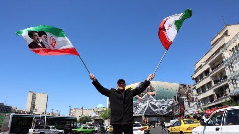 Un hombre iraní ondea banderas nacionales de Irán en la plaza Enghelab de Teherán, Irán, el 22 de abril de 2026.