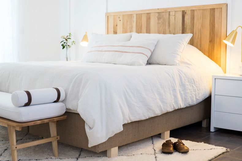 En el dormitorio matrimonial predomina una paleta de colores calmos y blanco. Detalles como el lino, la alfombra marroquí de lana, los muebles fabricados en madera de roble y la banqueta inspirada en los años 50 dan un look bohemio y relajado