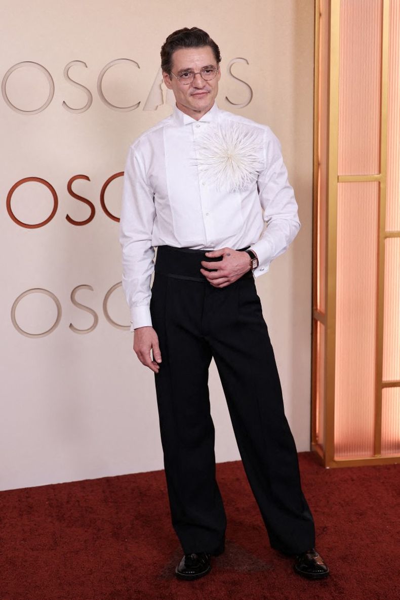 Pedro Pascal llegó al Dolby Theatre con el rostro afeitado y un atuendo compuesto por una camisa blanca con un aplique de plumas y un pantalón negro de tiro alto.  