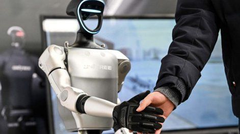 Un hombre estrecha la mano de un robot humanoide de Unitree Robotics durante la Conferencia Mundial de Desarrolladores celebrada en Shanghai el 21 de febrero de 2025
