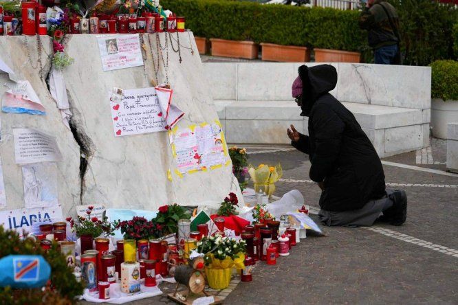 Una persona reza ante la estatua de Juan Pablo II en el exterior del Hospital Universitario Gemelli, donde el Papa Francisco está hospitalizado por neumonía, en Roma.