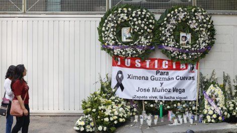 Dos personas observan unas ofrendas florales en la fachada de la funeraria donde fueron velados los restos de los funcionarios del gobierno capitalino mexicano, Ximena Guzmán y José Muñoz, asesinados en una de las principales avenidas de la Ciudad de México el 20 de mayo de 2025