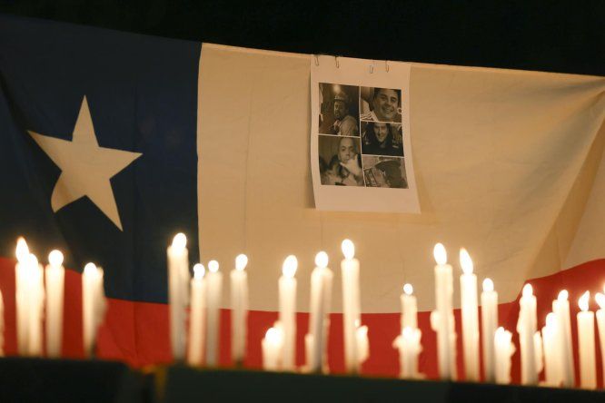 Fotografía de una bandera de Chile con retratos de los mineros atrapados en El Teniente este sábado, durante una vigilia en el control de acceso Los Maitenes, en Rancagua (Chile)
