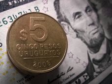 Imagen de un billete de dólares y una moneda de pesos uruguayos. Imagen de un billete de dólares y una moneda de pesos uruguayos.