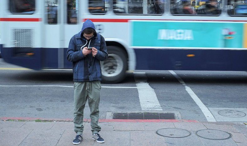 Adolescente mira su celular en el Centro de Montevideo.