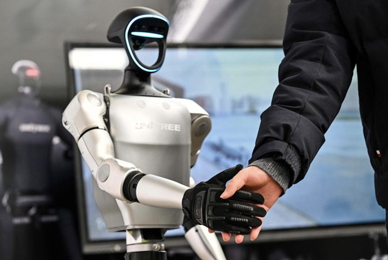 Un hombre estrecha la mano de un robot humanoide de Unitree Robotics durante la Conferencia Mundial de Desarrolladores celebrada en Shanghai el 21 de febrero de 2025