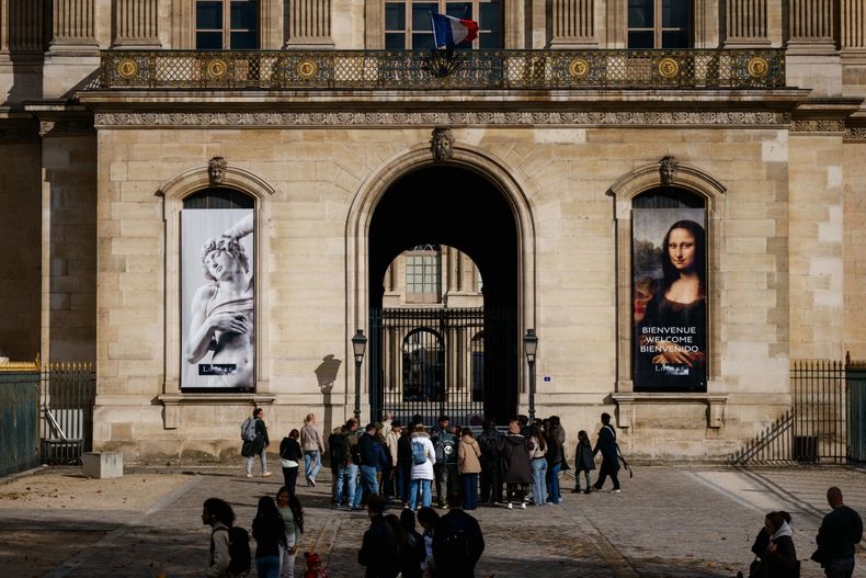 Los turistas reciben información del guía turístico frente a una entrada del patio cerrado de la pirámide del Louvre, después del anuncio de que el museo permanecerá cerrado a causa del robo.