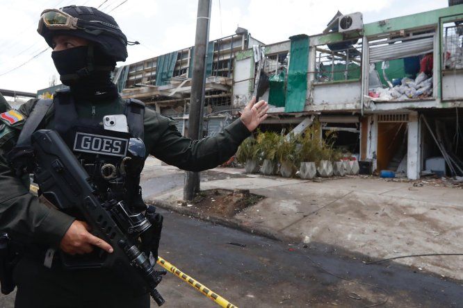 Un integrante de los Grupos Operativos Especiales de Seguridad (GOES) custodia casas afectadas por la explosión, este viernes en Cali (Colombia).&nbsp;