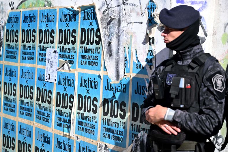 Un miembro de las Fuerzas Especiales Argentinas hace guardia junto a un muro con carteles que dicen “Justicia para Dios” cerca del juzgado de San Isidro, antes del inicio de la audiencia del juicio por la muerte de Diego Maradona en San Isidro, provincia de Buenos Aires, abril de 2025