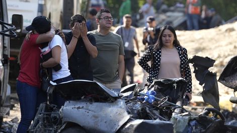 Familiares de las víctimas del atentado ocurrido en la Vía Panamericana lloran este domingo frente a los escombros de los vehículos destruidos, en Cajibío (Colombia).