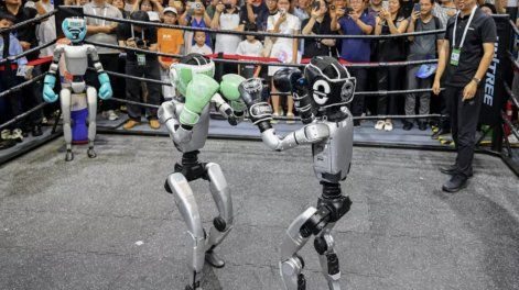 La gente observa a robots humanoides boxeando en una exhibición durante la Conferencia Mundial de IA en Shanghái, en julio de 2025
