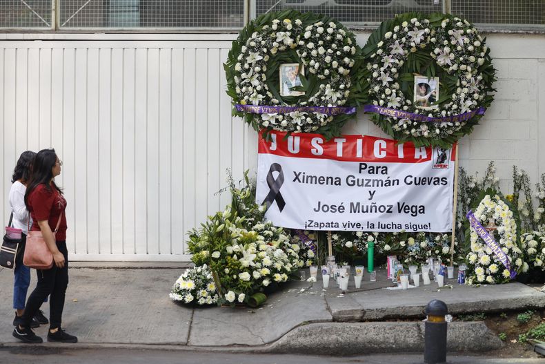 Dos personas observan unas ofrendas florales en la fachada de la funeraria donde fueron velados los restos de los funcionarios del gobierno capitalino mexicano, Ximena Guzmán y José Muñoz, asesinados en una de las principales avenidas de la Ciudad de México el 20 de mayo de 2025