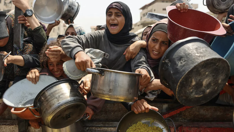 Palestinos esperan recibir comidas preparadas en un centro de distribución de alimentos en la ciudad de Gaza el 13 de agosto de 2025