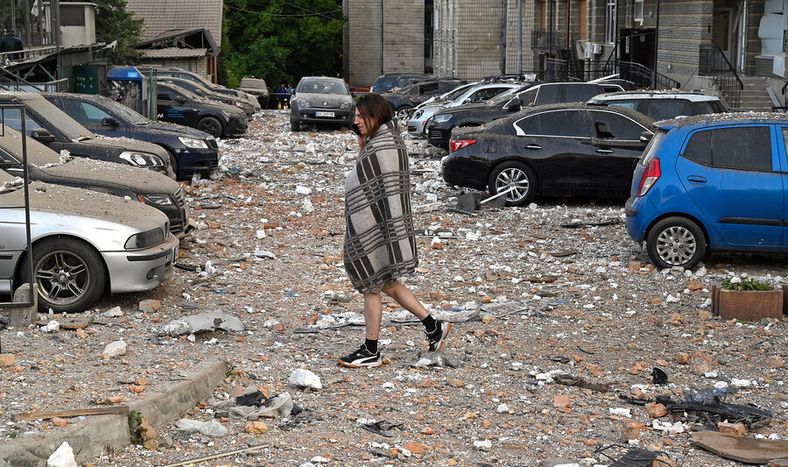 Residente camina entre autos dañados al salir de un edificio parcialmente destruido después de ataques con drones en Kiev. Foto: Oleksandr Popenko, PIJL