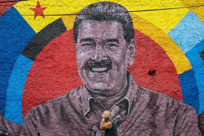 Una persona camina frente a un mural con la imagen del presidente de Venezuela, Nicolás Maduro, durante una manifestación este viernes, en Caracas (Venezuela).