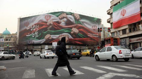 Una mujer iraní cruza una calle cerca de una valla publicitaria que dice “Irán es nuestra Patria” en la Plaza Enqelab de Teherán, Irán, este martes 13 de enero de 2025.