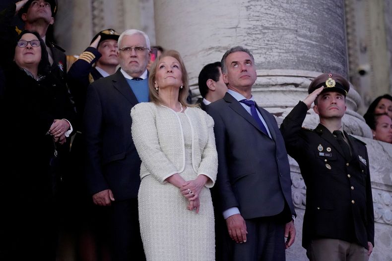 Carolina Cosse junto a Yamandú Orsi presenciando el arreo de los pabellones nacionales.